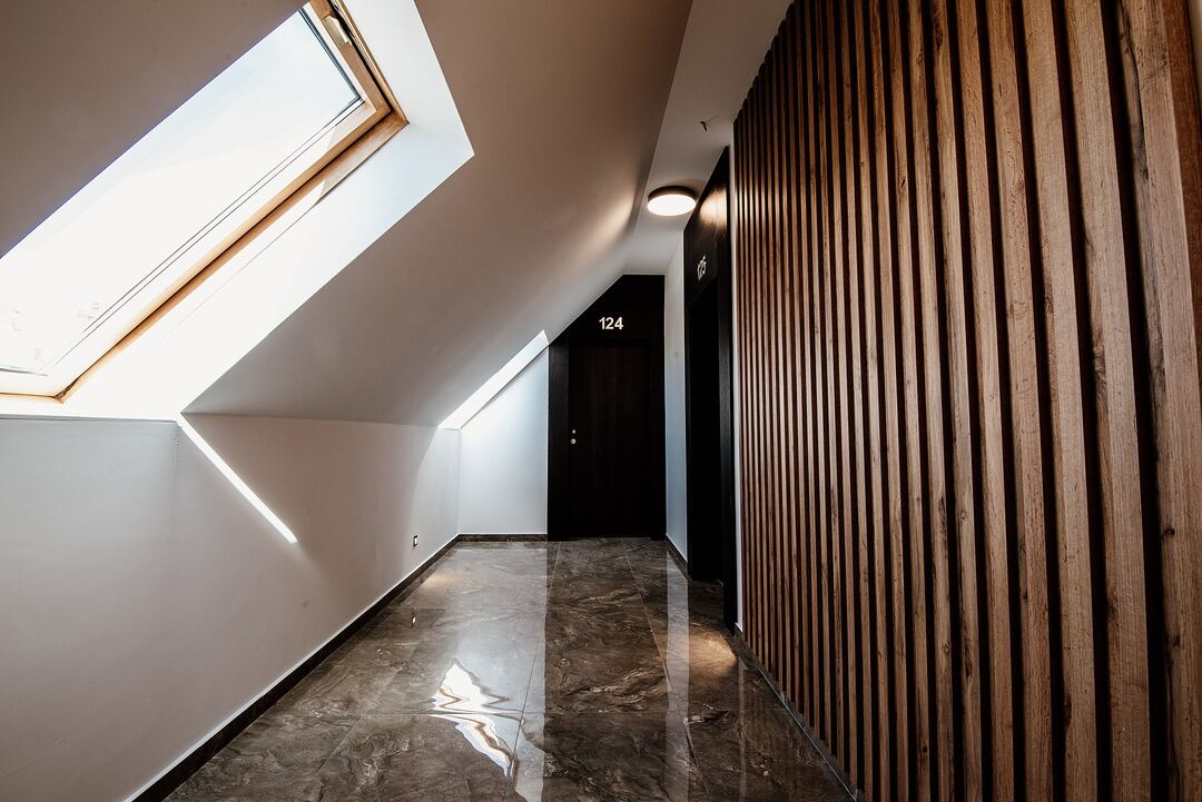 Modern hotel hallway with dark acoustic guest room door and marble floor